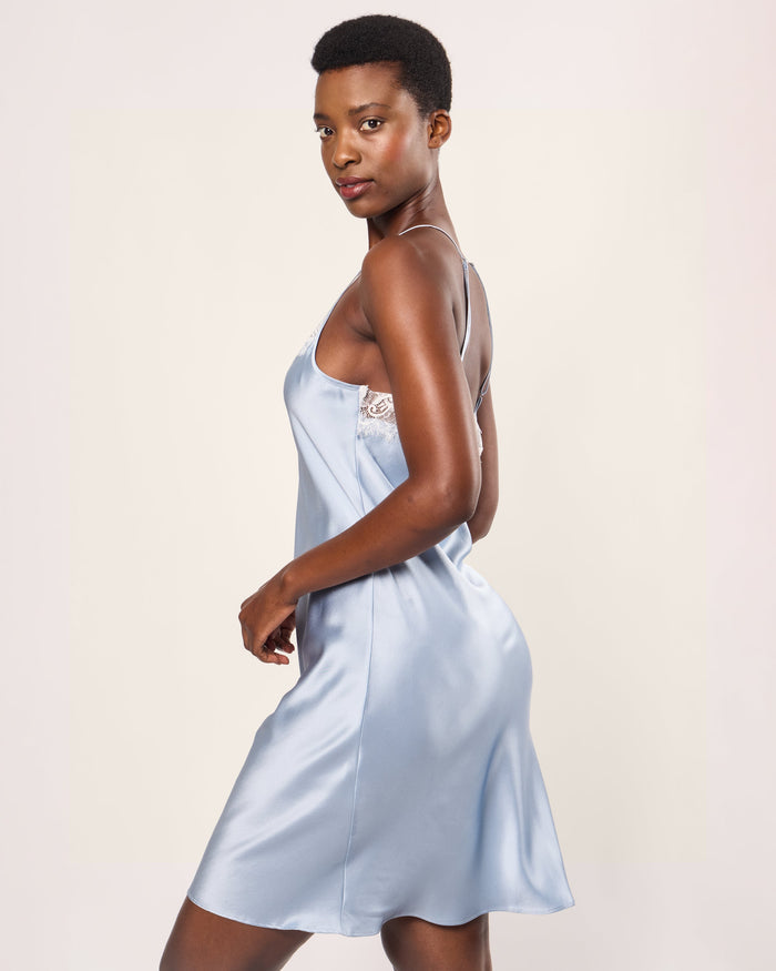 Woman wearing a light blue satin nightgown against a plain background