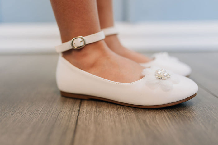 girl's white shoe with strap and flower on toe
