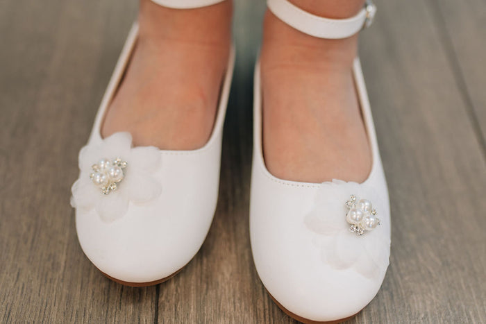 girl's white shoe with strap and flower on toe