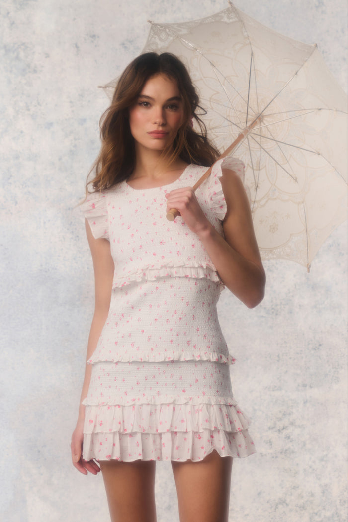 Woman in a white dress holding a white umbrella against a light background