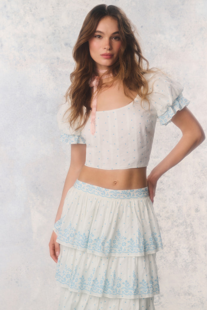 Woman wearing a light blue and white outfit with a textured background