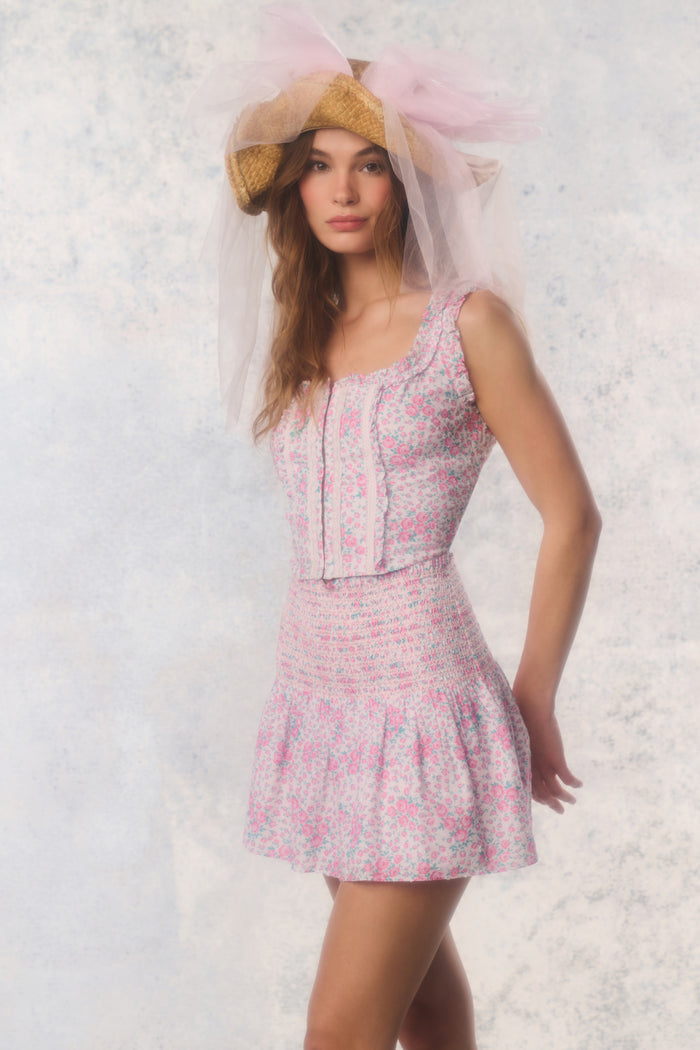 Woman wearing a pink floral dress and matching headpiece against a light background