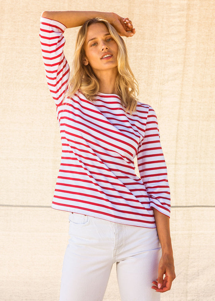 Woman wearing a red and white striped shirt against a beige wall | Lead