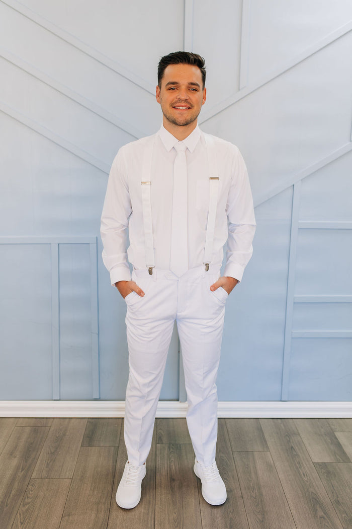 Man in all white pants, button up shirt, tie, and suspenders.