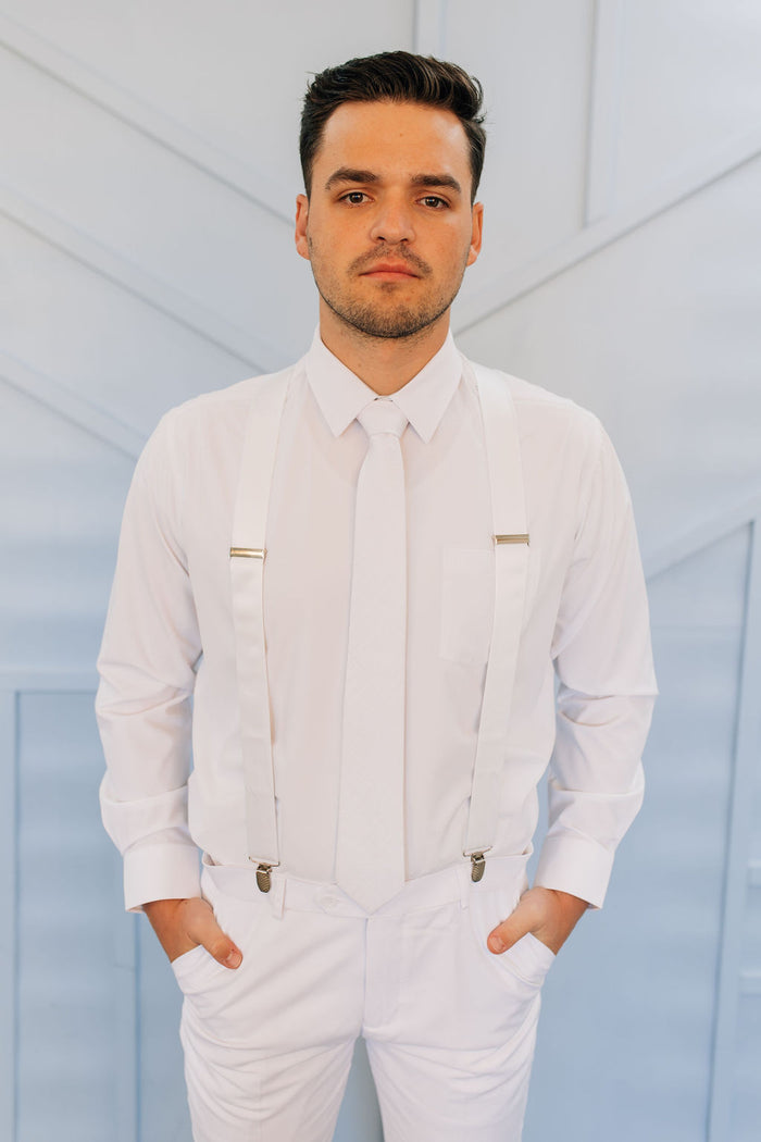 Man in all white pants, button up shirt, tie, and suspenders.