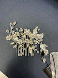 Silver hair comb with decorative leaves and crystals on a dark surface