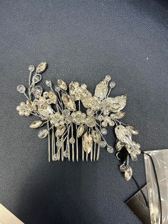 Silver hair comb with decorative leaves and crystals on a dark surface