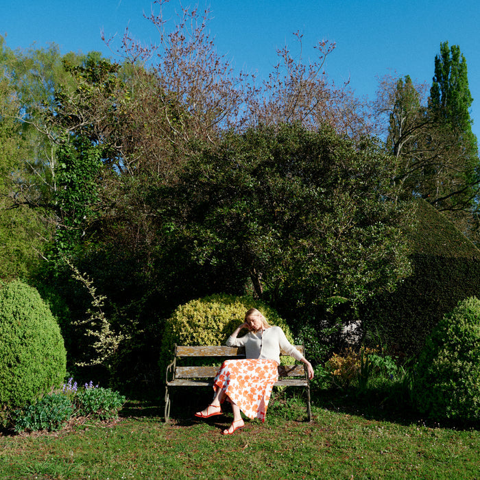 Woman sitting on a bench in a park with trees and greenery around