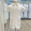 White knit baby romper with decorative pockets.