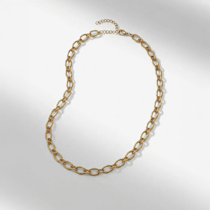 A gold chain necklace with elongated oval links and a short extender chain with a clasp, displayed on a light gray background. | Lead