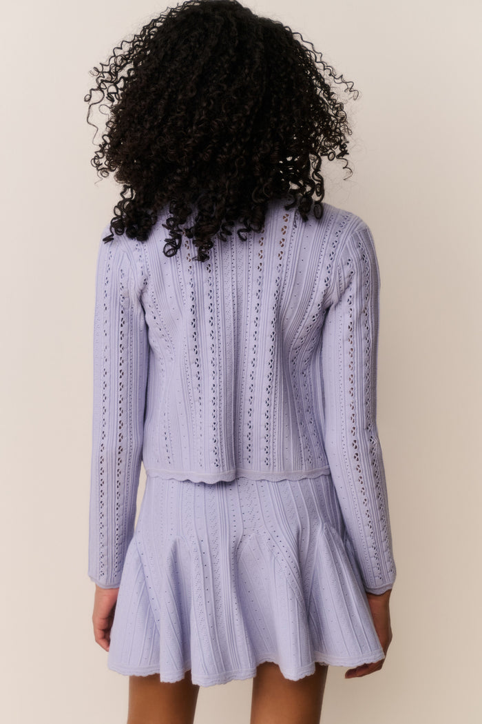Tween wearing a white knit sweater and matching dress on a plain background