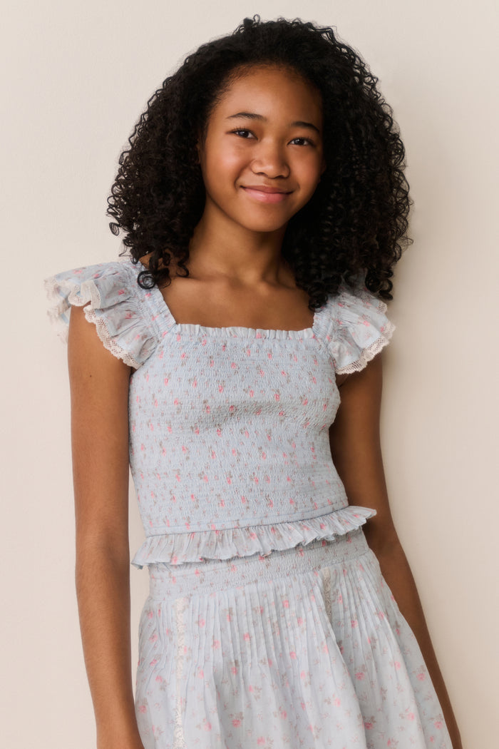 Girl wearing a Light blue top with floral pattern and matching skirt on a beige background