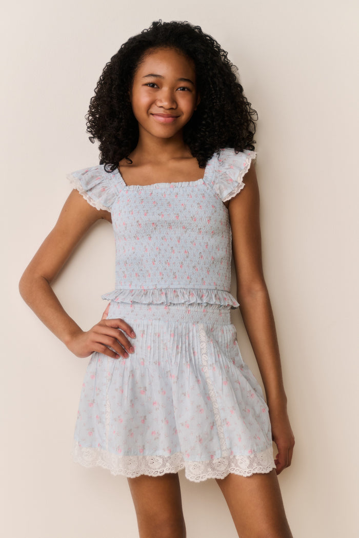 Girl wearing a Light blue top with floral pattern and matching skirt on a beige background