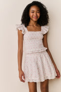 Girl wearing white floral ruffle shirt and matching skirt against white background