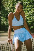 Girl in a blue active set leaning on a tennis net
